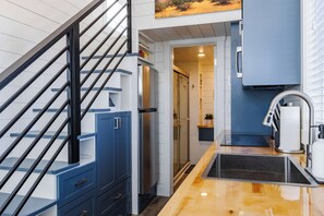 A modern kitchen with a wooden countertop, stainless steel appliances, and a blue cabinetry. - Zion Stay • Pet-Friendly Tiny Home (Apple Valley)