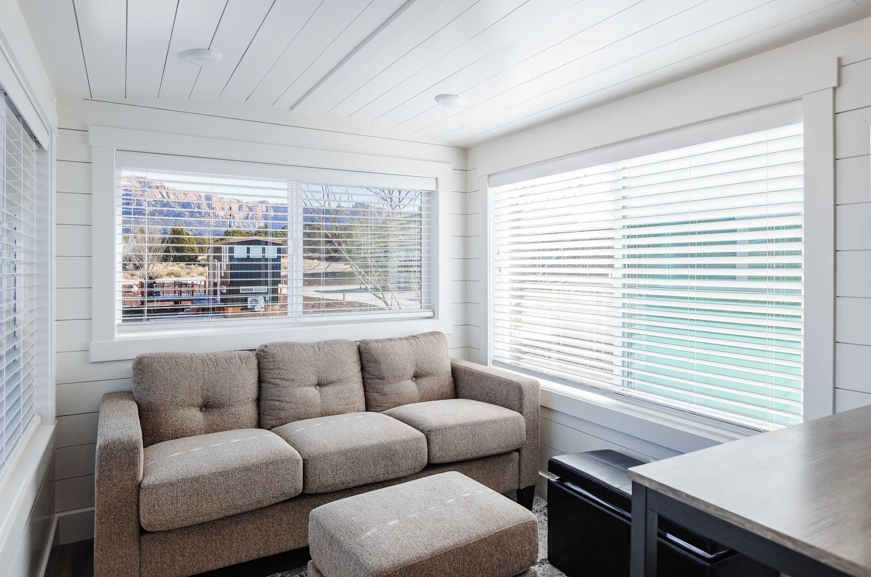 A modern room with a built-in window seat, a sofa, and a desk.