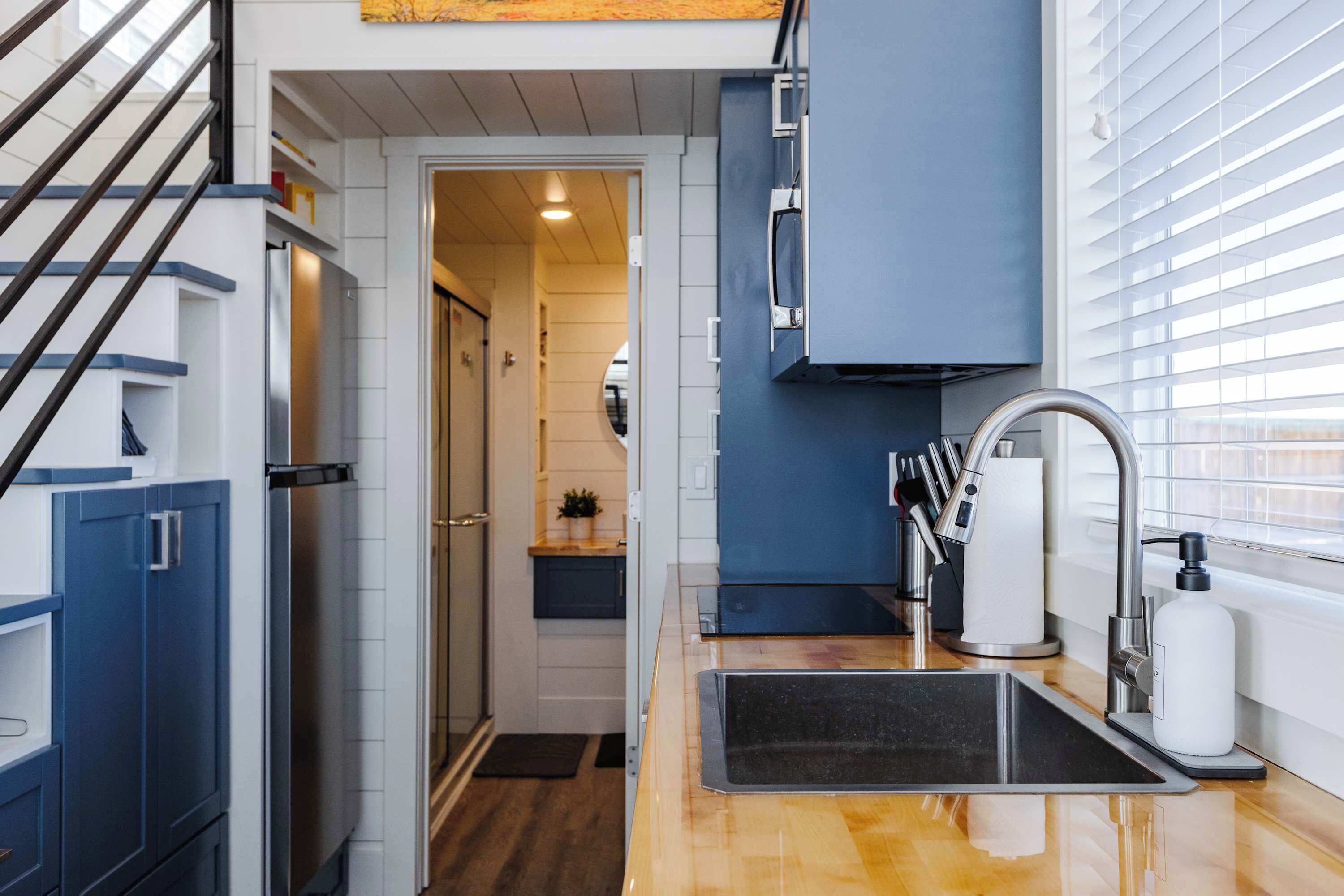 Functional kitchen with refrigerator, microwave, cooktop, sink, and storage for preparing breakfast, dinner, or snacks during your stay.