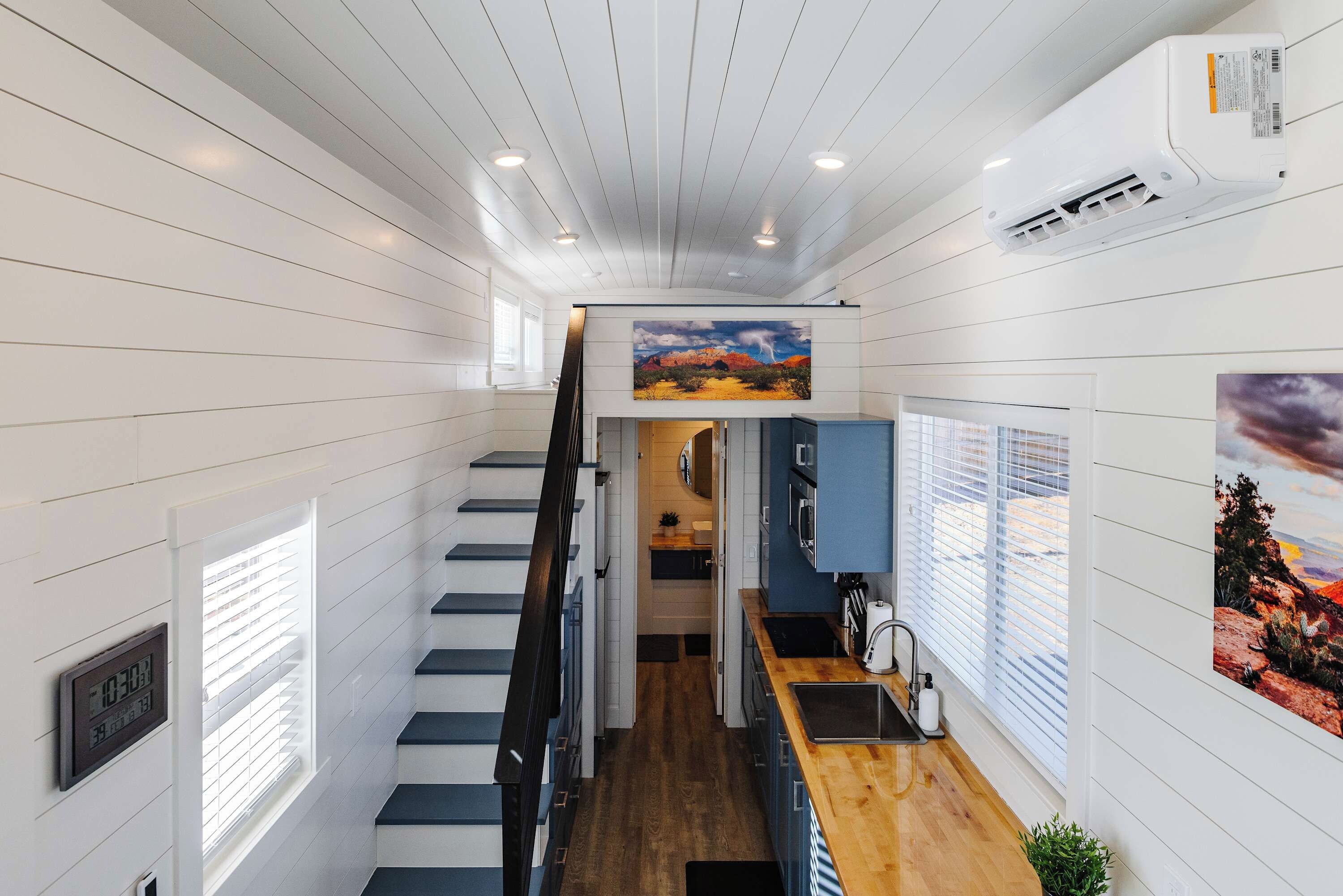 A modern interior with a wooden staircase, a kitchen area, and artwork on the walls.