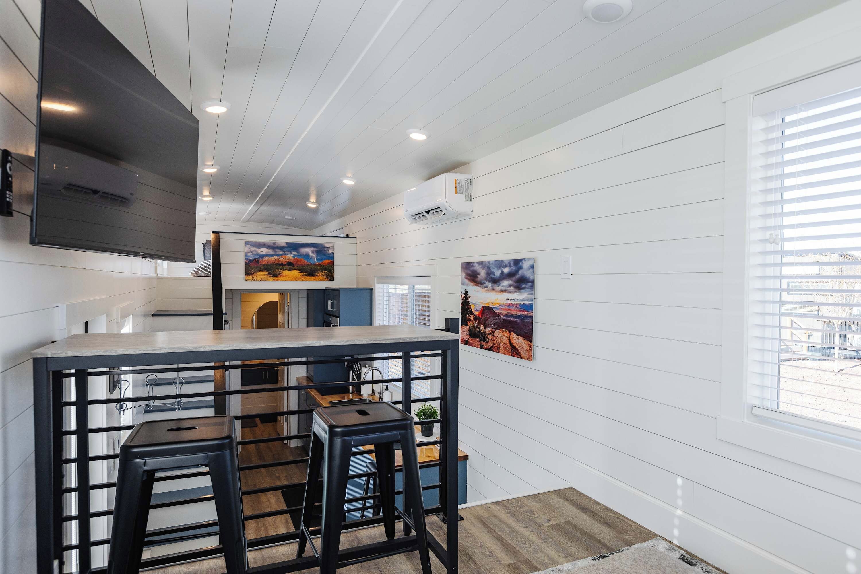 A modern kitchen with a central island, bar stools, and artwork on the walls.