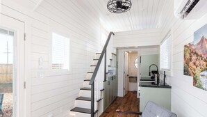 Interior moderno com escada, piso de madeira e área de jantar com vista para o exterior.
