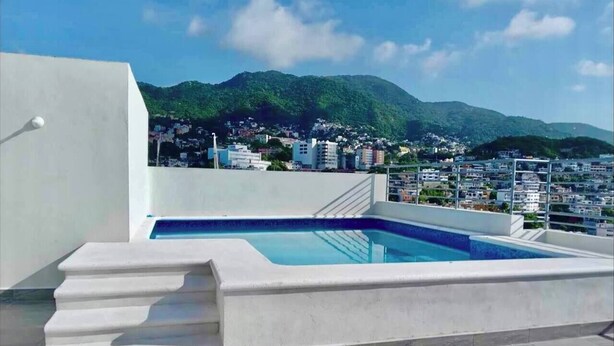 A rooftop pool with a view of a cityscape and mountains in the background. - Apartment with a beautiful view of the Bay (Acapulco de Juárez)