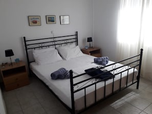 A neatly made bed with white linens, two bedside tables with lamps, and three framed pictures on the wall. - Ionian Balcony Davgata (Kefalonia)