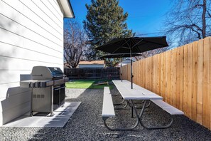 An outdoor patio with a grill, picnic table, and umbrella. - Arvada Retreat | Garage | Near Olde Town+Red Rocks (Arvada)
