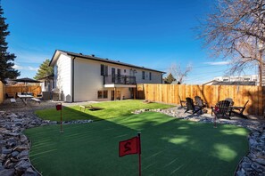 A house with a backyard containing a small artificial green lawn with a flag, a wooden fence, and outdoor furniture. - Arvada Retreat | Garage | Near Olde Town+Red Rocks (Arvada)