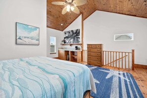 Ein Schlafzimmer mit Bett, Schreibtisch, Stuhl und Fenster.