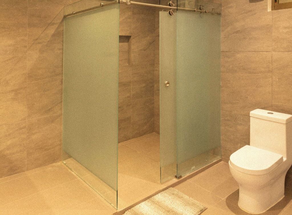 Ein Badezimmer mit einer Duschkabine, einer weißen Toilette und einem gefliesten Boden.