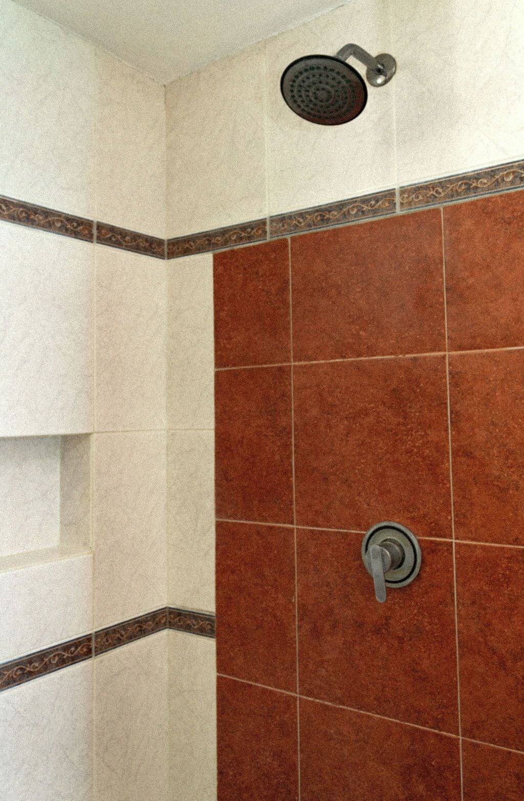 A shower with a handheld showerhead and a wall-mounted control valve.