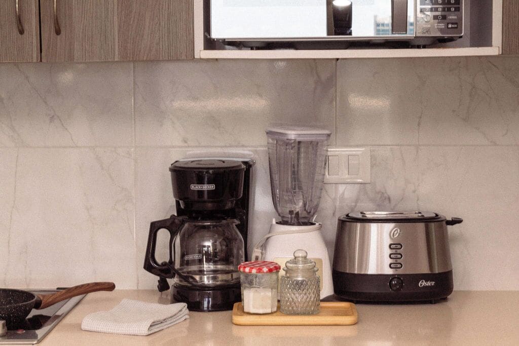 Une cuisine équipée d’une machine à café, d’un mixeur, d’un grille-pain et d’une planche à découper avec un pot et un salier.