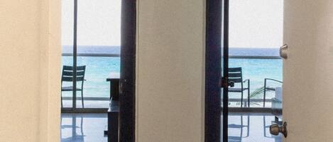 A corridor with glass doors leading to a balcony with a view of the sea.