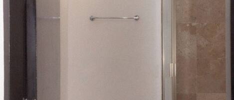 A bathroom with a toilet, a small window, and a shower area.