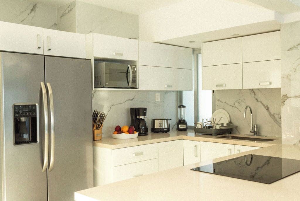 A modern kitchen with a stainless steel refrigerator, a microwave, a coffee maker, and a blender on the countertop.
