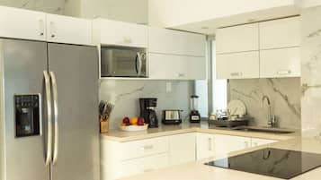 A modern kitchen with a stainless steel refrigerator, a microwave, a coffee maker, and a blender on the countertop.