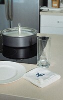 Una encimera de cocina con una olla, un vaso y una servilleta con diseño azul.