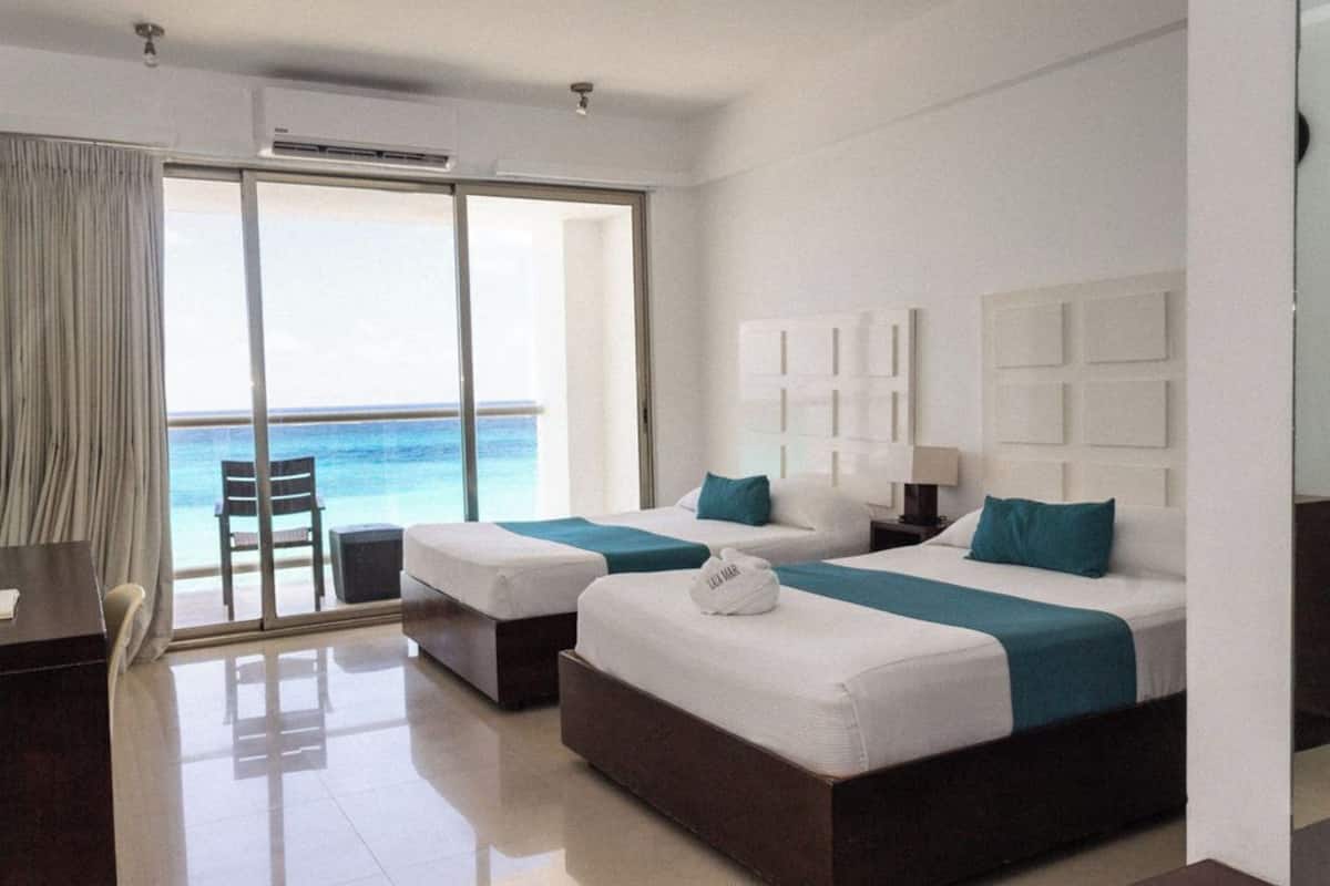 A hotel room with two beds, a desk, and a chair.