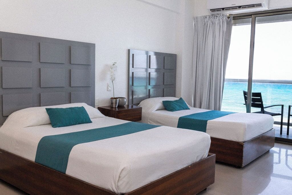 A hotel room with two beds, a large window with a view of the sea, and a modern design.