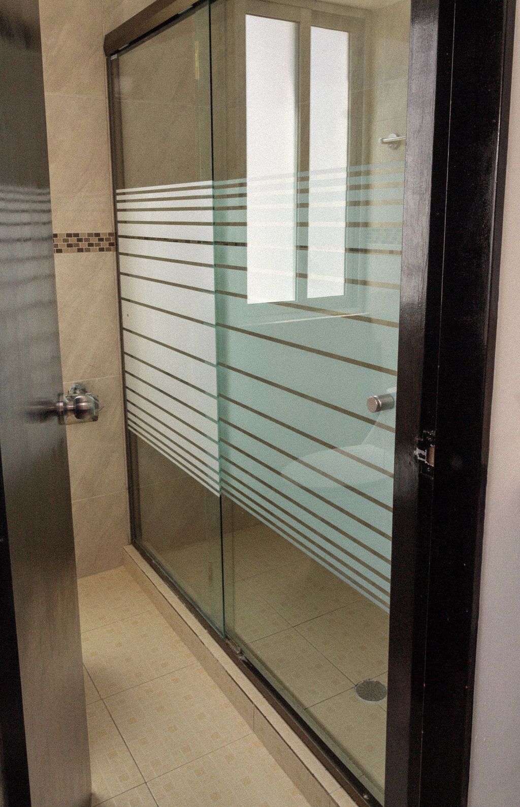A glass door with horizontal lines, a metal handle, and a tiled floor.