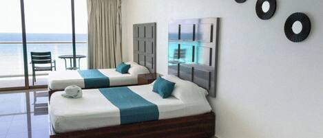 A hotel room with two beds, a balcony with a view of the sea, and a large window.