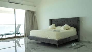 A modern bedroom with a large bed, a glass floor, and a view of the sea.