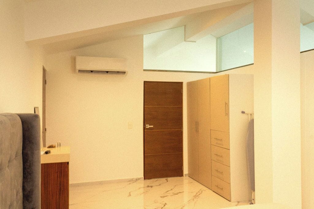 Una habitación de hotel moderna con piso de mármol, armario empotrado, un escritorio pequeño y un ventanal grande.