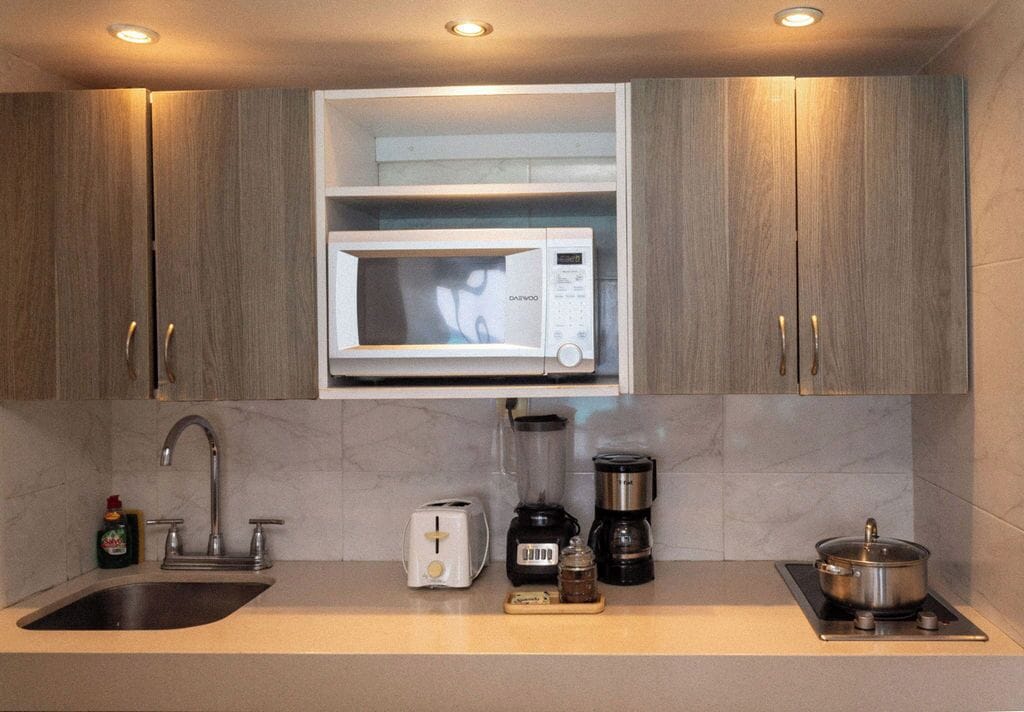 A modern kitchen with a built-in microwave, a toaster, a blender, and a stove.