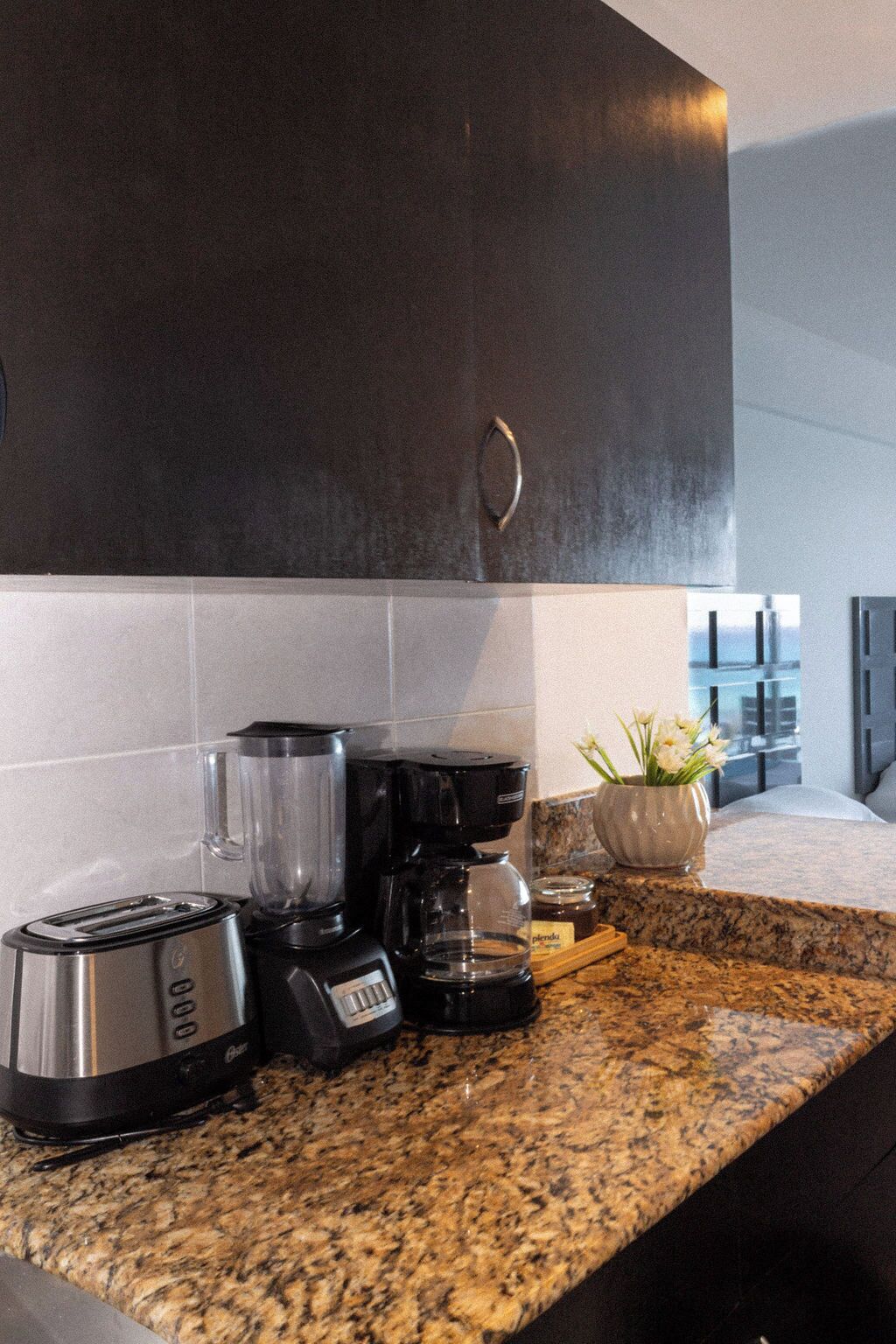 A kitchen with a toaster, coffee maker, and blender on a granite countertop.