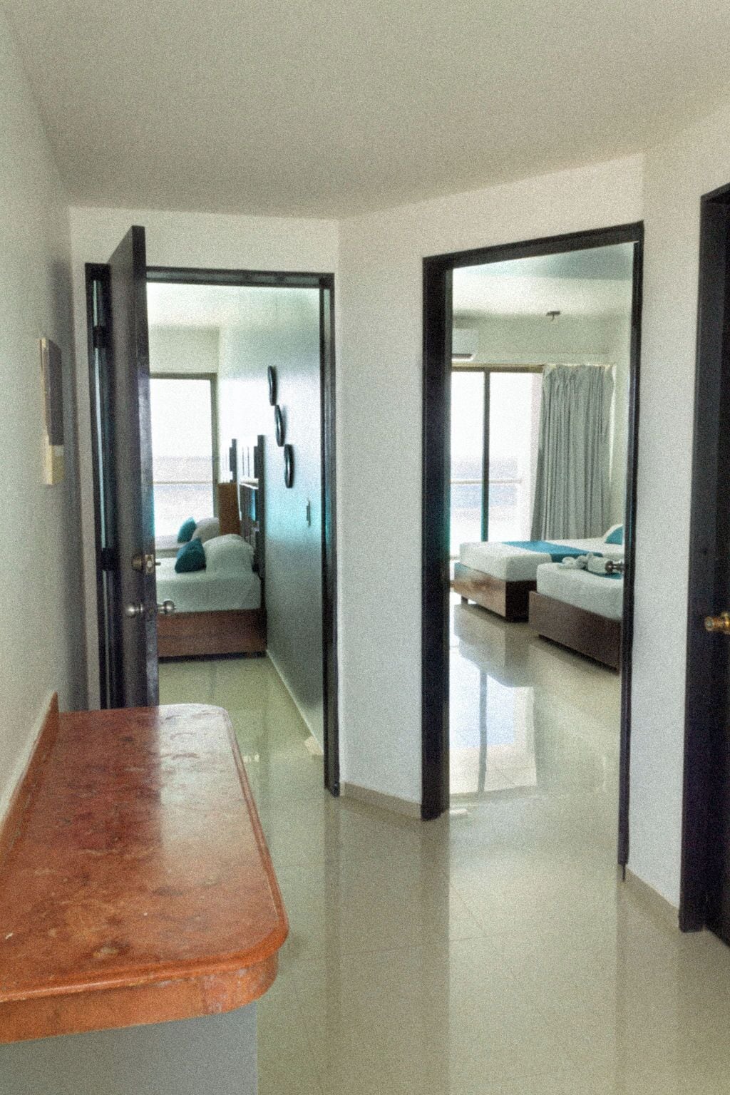Ein Hotelzimmer mit Bett, Schreibtisch und Blick auf ein weiteres Zimmer.