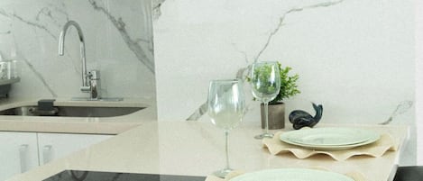 A modern kitchen with a marble backsplash, a built-in sink, and a glass-top dining table with a decorative runner.