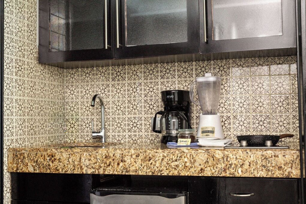 Una cocina con encimera de granito, cafetera, licuadora y sartén.
