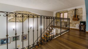 Eine Treppe mit aufwendiger Metallreling, Holzboden und einer Steinwand mit einer Gitarre.