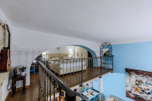 A multi-level living space with a staircase, a sofa bed, a dining area, and a wall-mounted artwork. - Castle Hill Loft Heart Cagliari by Yamar Villas (Cagliari)