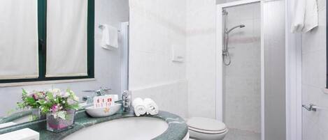 Un baño con lavamanos de mármol, inodoro, ducha y espejo.