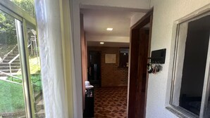 Ein Korridor mit einem Schachbrettmuster-Bodenbelag, einem Fenster mit Vorhängen und einer Tür zu einem weiteren Raum.