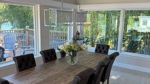 Un coin repas avec une table en bois, des chaises noires et un vase de fleurs.