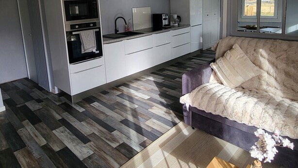 A modern kitchen with built-in appliances and a dining area with a sofa and a coffee table. - Nature getaway: cottage with grounds (Saint antheme)