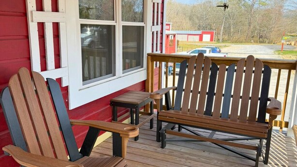 A wooden deck with two Adirondack chairs and a small table. - 3-bedroom Bird's Nest Lodge in pleasant Cave Spring with AC and charm (Cave Spring)