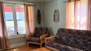 A living room with a sofa, two armchairs, a wooden coffee table, and a window with curtains. - 3-bedroom Bird's Nest Lodge in pleasant Cave Spring with AC and charm (Cave Spring)