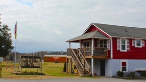 A red building with a balcony and a flagpole. - 3-bedroom Bird's Nest Lodge in pleasant Cave Spring with AC and charm (Cave Spring)