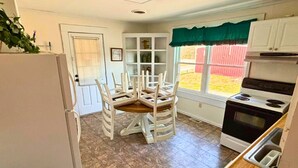 A compact kitchen with white cabinets, a built-in oven, and a dining table with chairs. - 3-bedroom Bird's Nest Lodge in pleasant Cave Spring with AC and charm (Cave Spring)