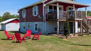 A two-story house with a balcony, a garage, and a lawn with red chairs. - 3-bedroom Bird's Nest Lodge in pleasant Cave Spring with AC and charm (Cave Spring)
