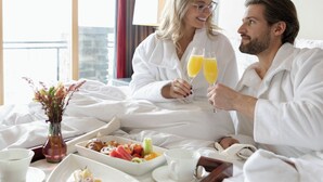 Una habitación de hotel con una cama, una bandeja de desayuno y un jarrón con flores.
