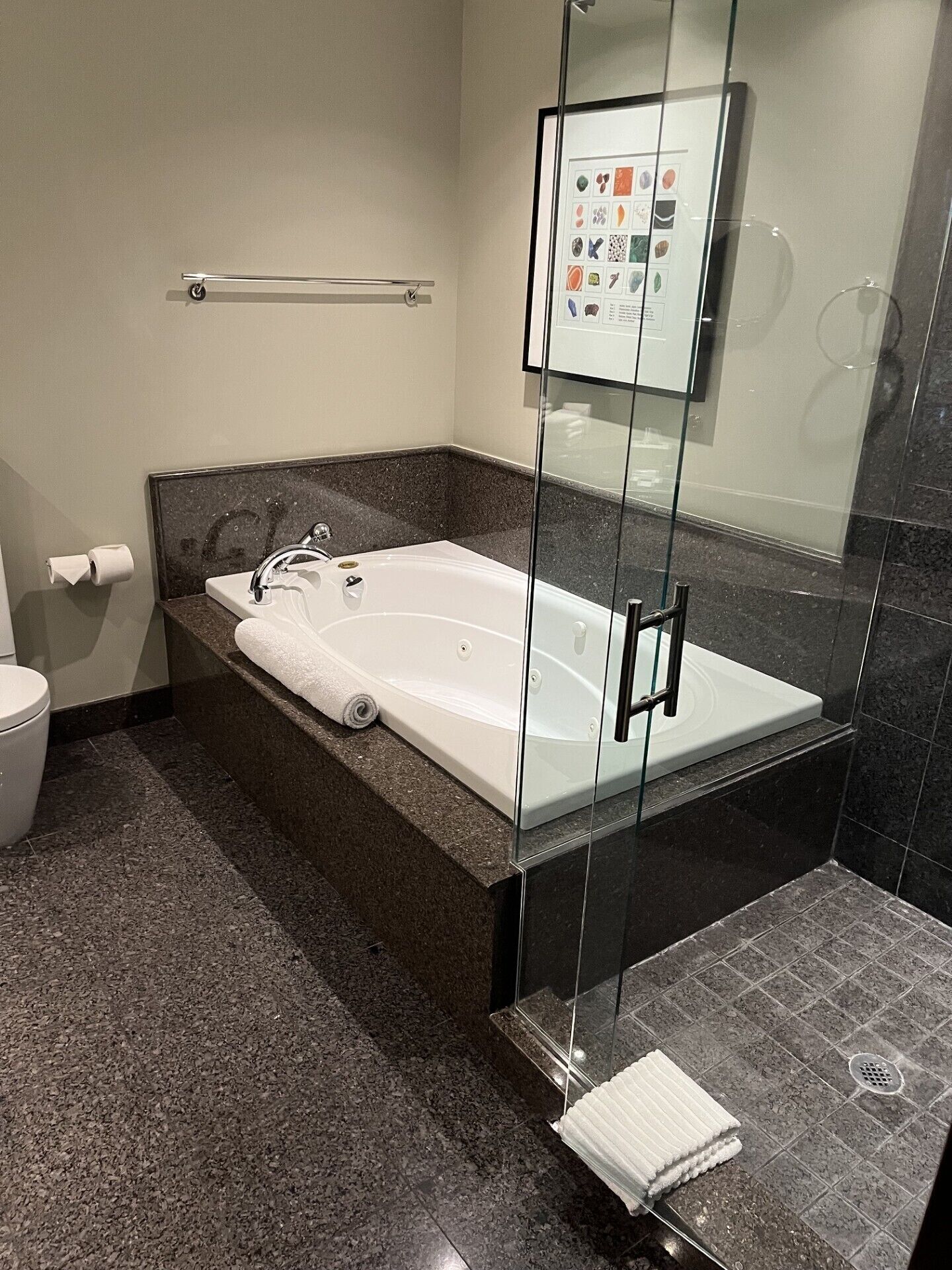 A modern bathroom with a freestanding bathtub, a glass shower enclosure, and a marble-tiled floor.