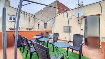 An outdoor patio with tables and chairs, a pergola, and a satellite dish.