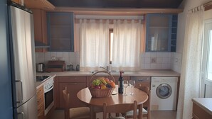 Una cocina compacta con una mesa de comedor, lavadora y refrigerador.