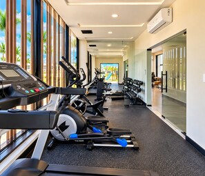 A modern gym with cardio equipment, weight machines, and a mirrored wall. - A Peaceful Retirement in Punta Cana (Punta Cana)