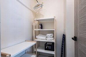 Ett litet, välordnat förvaringsutrymme med hyllor, ett bord och ett svart kassaskåp.