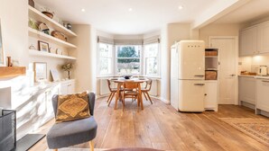 Eine moderne Küche mit weißen Schränken, einem eingebauten Kühlschrank und einem Essbereich mit rundem Tisch und Stühlen.