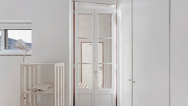 Une chambre avec un berceau, une armoire blanche et une fenêtre.