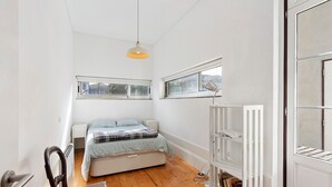 Une chambre à coucher avec un lit, une chaise, un radiateur et une bibliothèque.